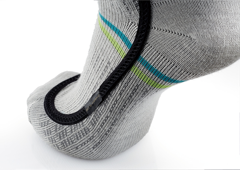 Graue Skiheizungssocke Detailaufnahme einer grauen Ski Heat Race S.E.T Socke mit blauen und grünen Streifen und schwarzem Heizelement.