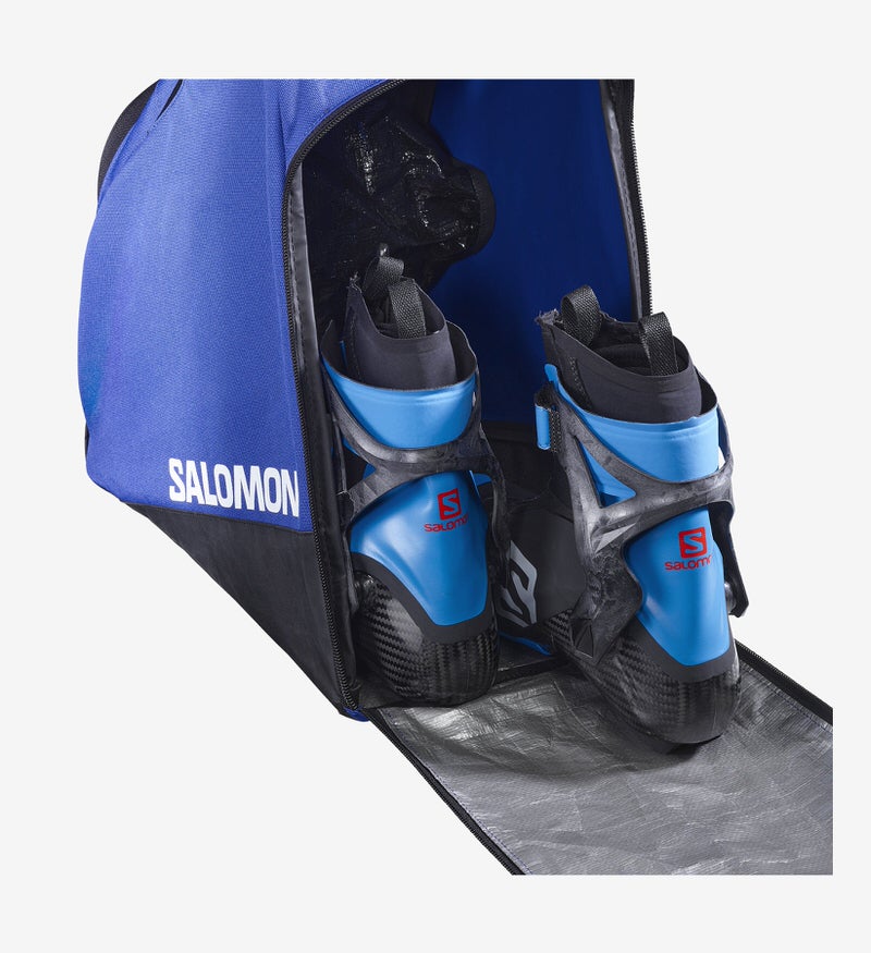 Offene blaue Salomon Skischuhtasche mit Skischuhen im Inneren, silberner Innenraum.