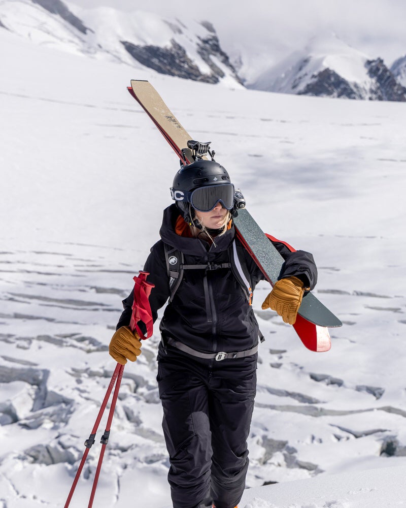 Skifahrer in Berglandschaft Person in schwarzer Gore-Tex Jacke und Skihose mit Skiern und Stöcken in verschneiter Berglandschaft.