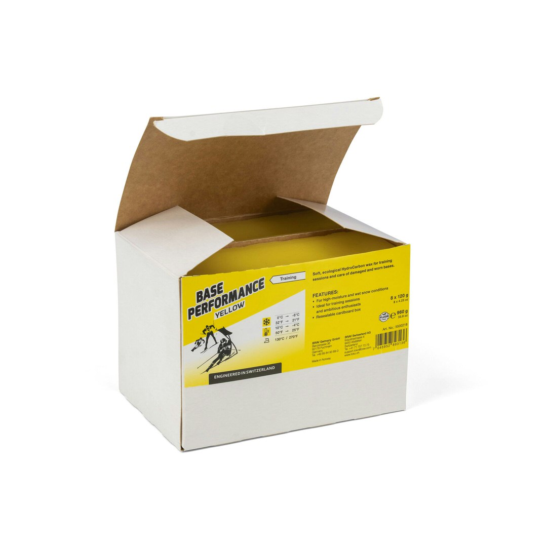 Offene Verpackung Toko Base Performance Yellow Heisswachs mit gelbem Aufdruck und Skifahrer-Illustration.