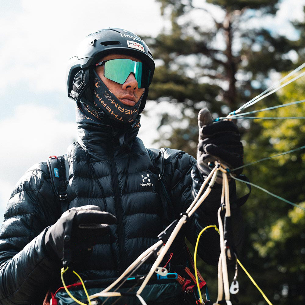 Person mit Helm, Skibrille, Daunenjacke und Therm-ic Handschuhen hält Seile. Fokus auf Grip und Wärmeleistung.