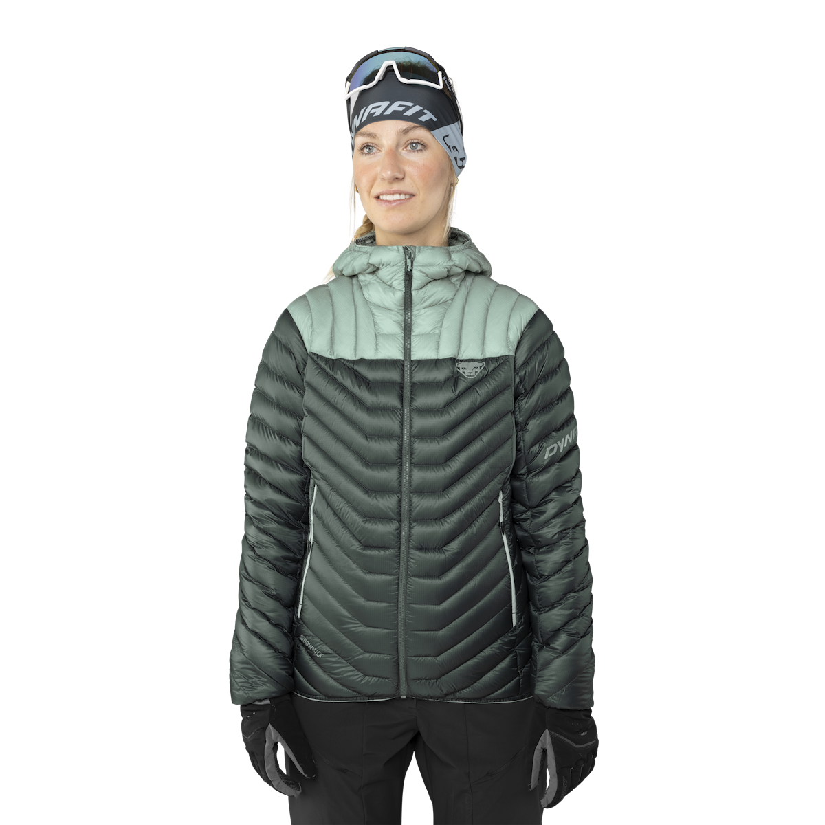 Frau in Daunenjacke mit Kapuze, grün und grau, trägt Stirnband und Handschuhe.