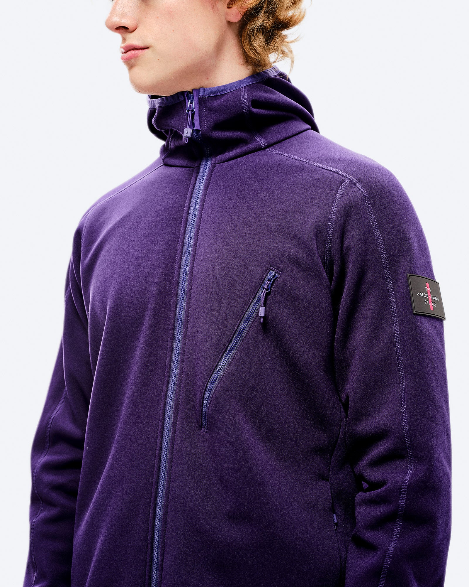 Lila M-7 Tech Fleece Jacke Nahaufnahme einer lila M-7 Tech Fleece Hood Jacke mit Kapuze und Reißverschluss.