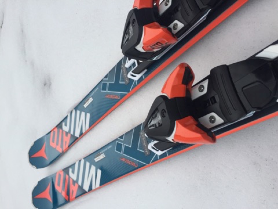 Ride Atomic Redster 2016! Ab jetzt bei uns erhältlich. Zwei blaue Atomic-Ski mit orangen Akzenten liegen auf hellem Schnee, die Bindungen sind schwarz und orange.
