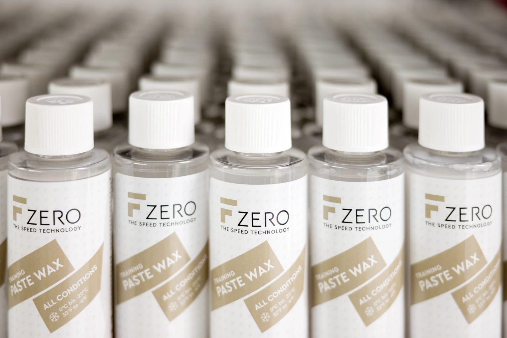 Viele Flaschen F Zero Paste Wax mit weißen Deckeln in mehreren Reihen. Auf den Etiketten ist das Logo und "Paste Wax" zu lesen.