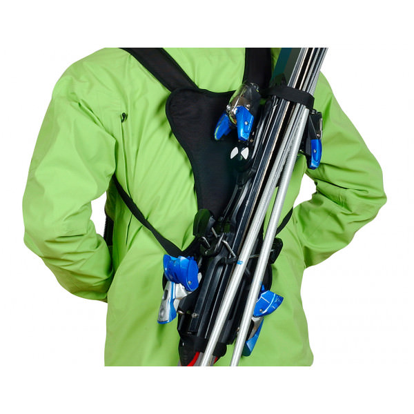 Ski-Träger im Anorak Person mit grünem Anorak trägt Ski mit dem Skiback wie einen Rucksack.