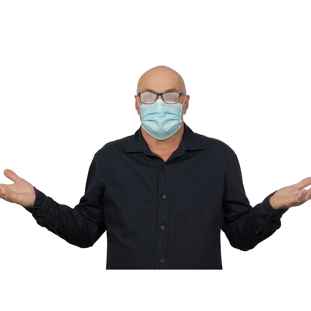 Mann mit beschlagener Brille und Maske. Er spreizt ratlos seine Arme aus.