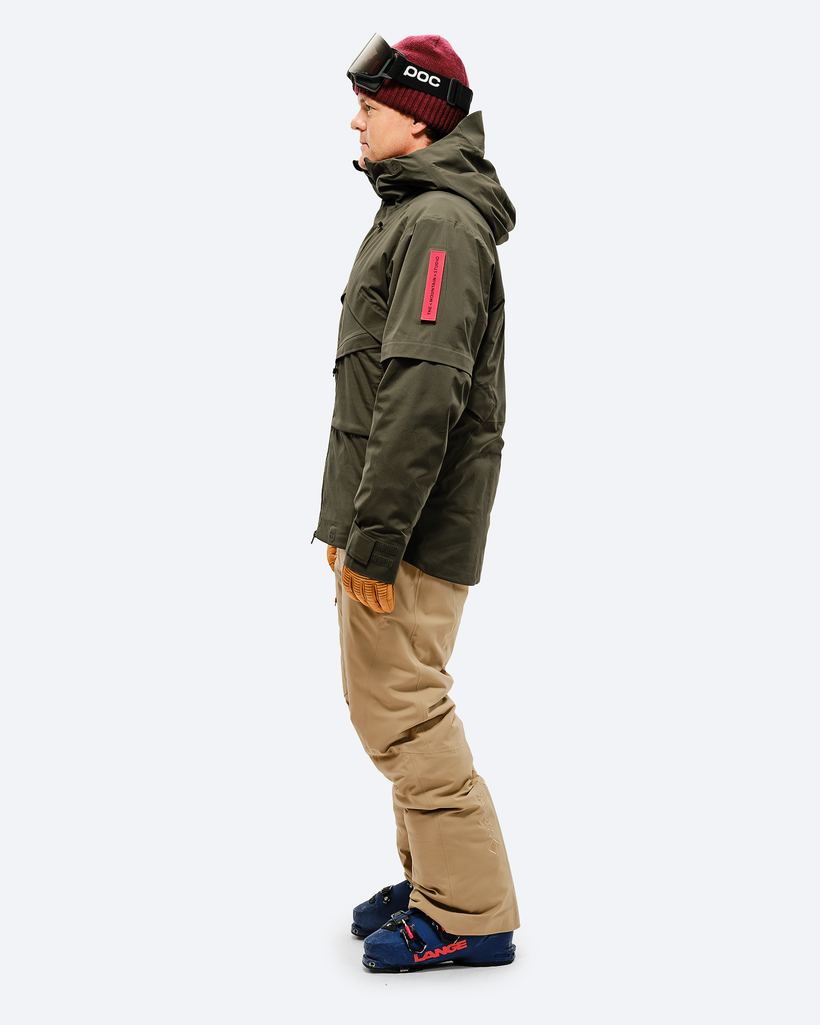 Ski-Outfit seitliche Ansicht Person von der Seite in Ski-Outfit mit Sandfarbener GORE-TEX 2L Stretch Insulated Pant und Skischuhen.