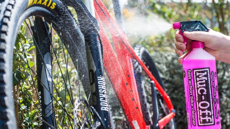 Reinigung eines Fahrrads mit Muc-Off Nano Tech Reiniger aus rosa Sprühflasche. Fahrrad wird sauber gesprüht.
