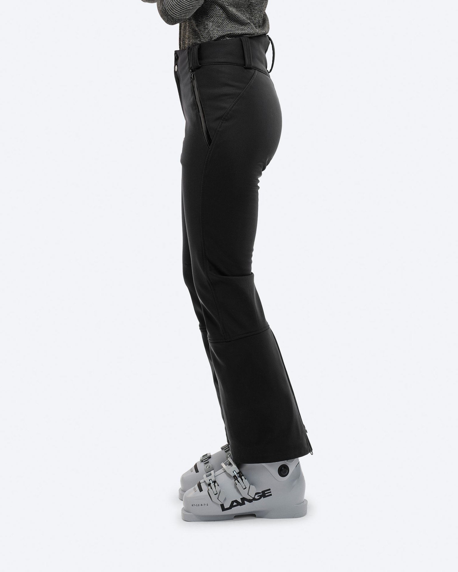 Schwarze Stretch-Skihose Profilansicht: Schwarze Stretch-Skihose mit Skischuhen. Reißverschlussdetail am Bein.
