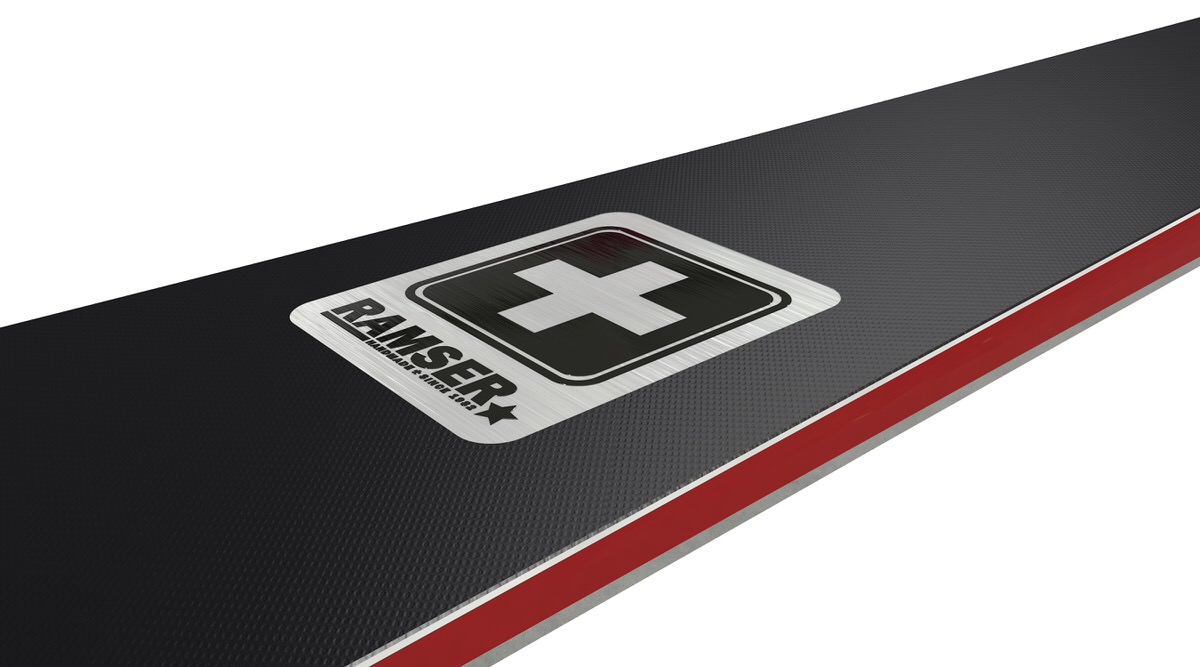 Ski mit Ramser Logo Detailansicht vom Ski mit Ramser Logo und Schweizer Kreuz auf schwarzem Hintergrund mit rotem Rand.