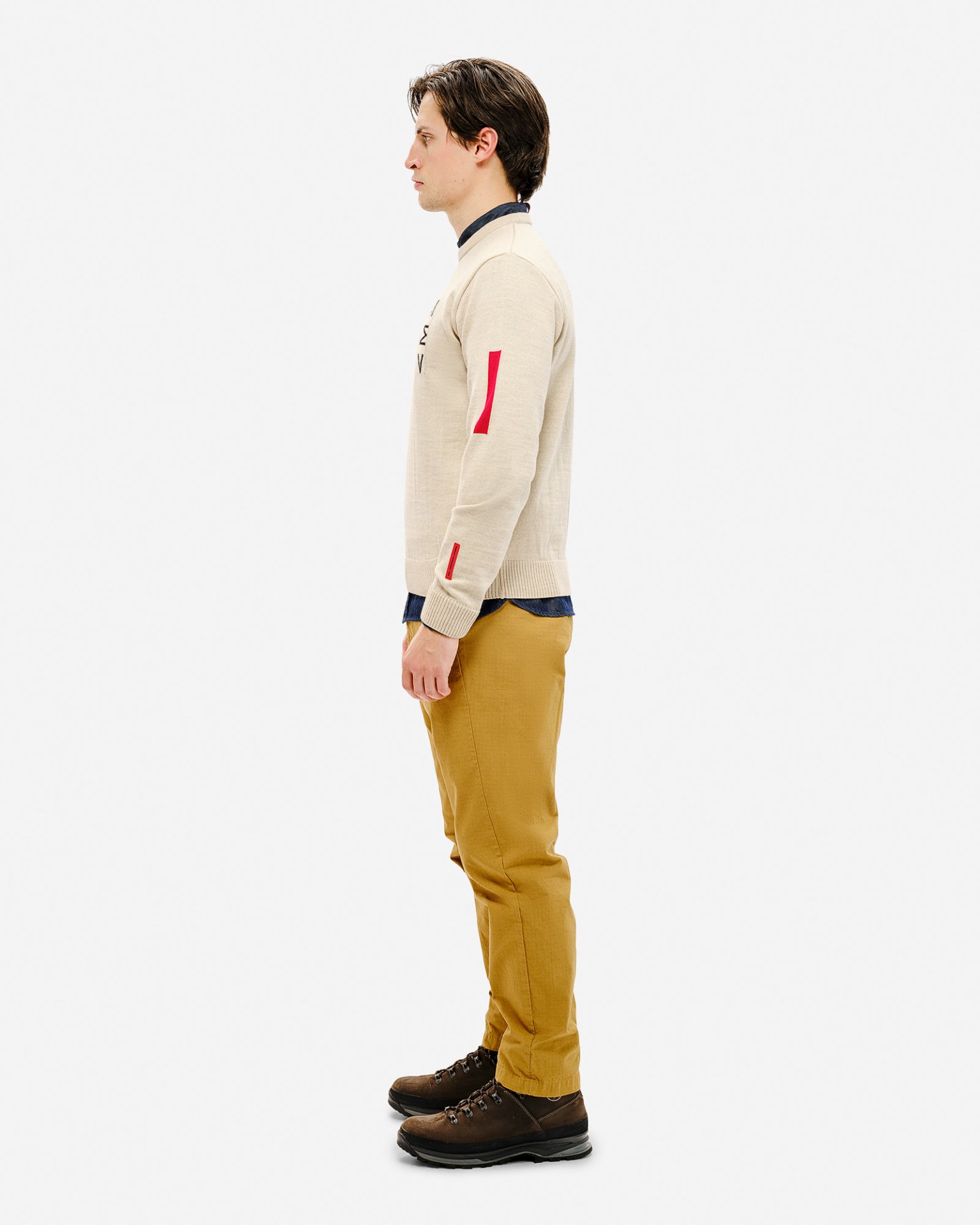 Mann im Ski Sweater Mann im Profil mit Ski Sweater St. Moritz, beiger Pullover mit roten Details und gelben Hosen.