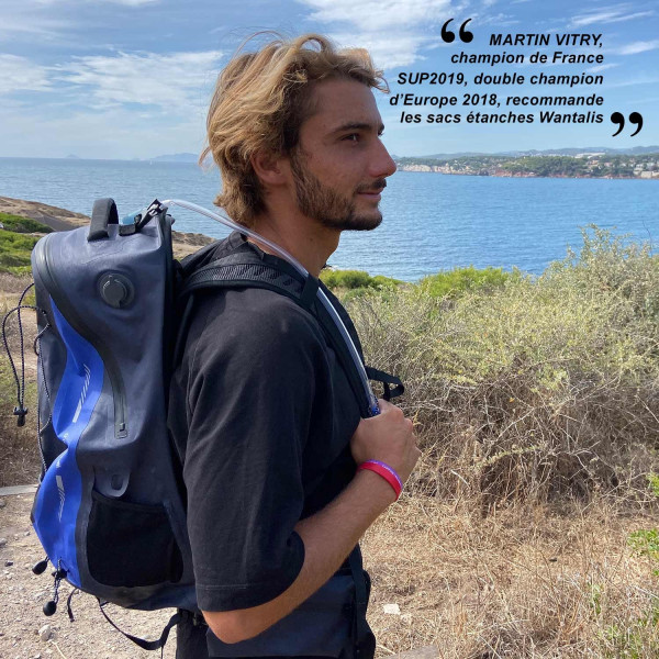 Mann mit wasserdichtem 35L Rucksack mit Trinksystem vor Küstenlandschaft. Zitat von Martin Vitry im Hintergrund.