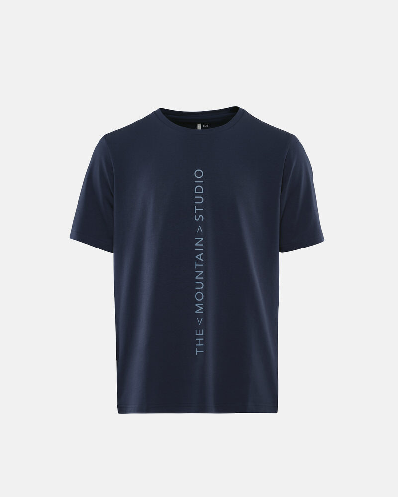 Dunkelblaues T-Shirt mit vertikalem "The Mountain Studio" Schriftzug.