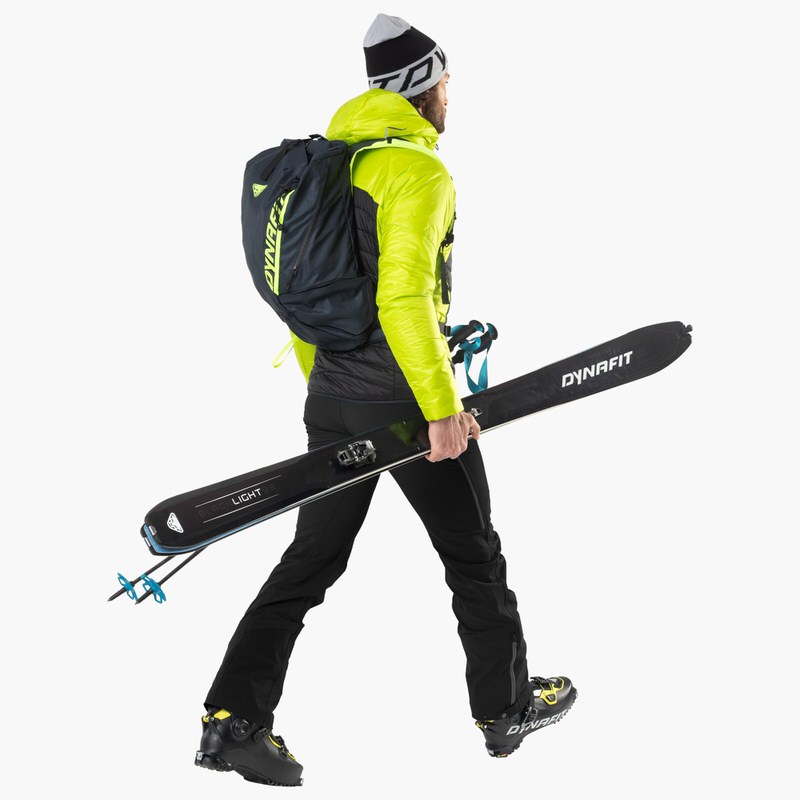 Mann mit Ski und Rucksack Ein Mann mit Rucksack und Dynafit Blacklight 95 Ski unter dem Arm, seitliche Ansicht.