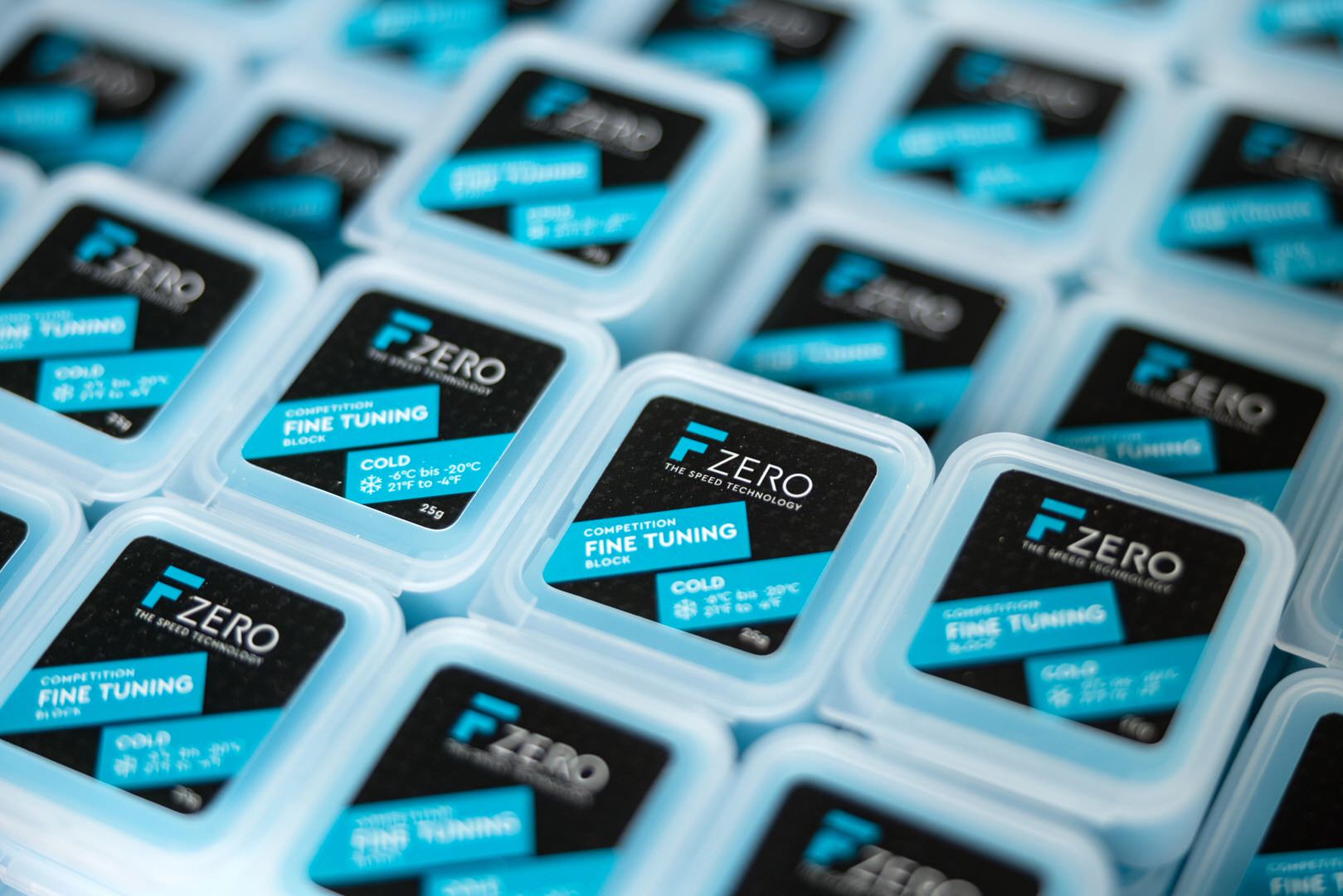 Viele blaue, quadratische Behälter mit schwarzen Etiketten mit blauen Akzenten und der Aufschrift "FZERO FINE TUNING" liegen dicht aneinander.