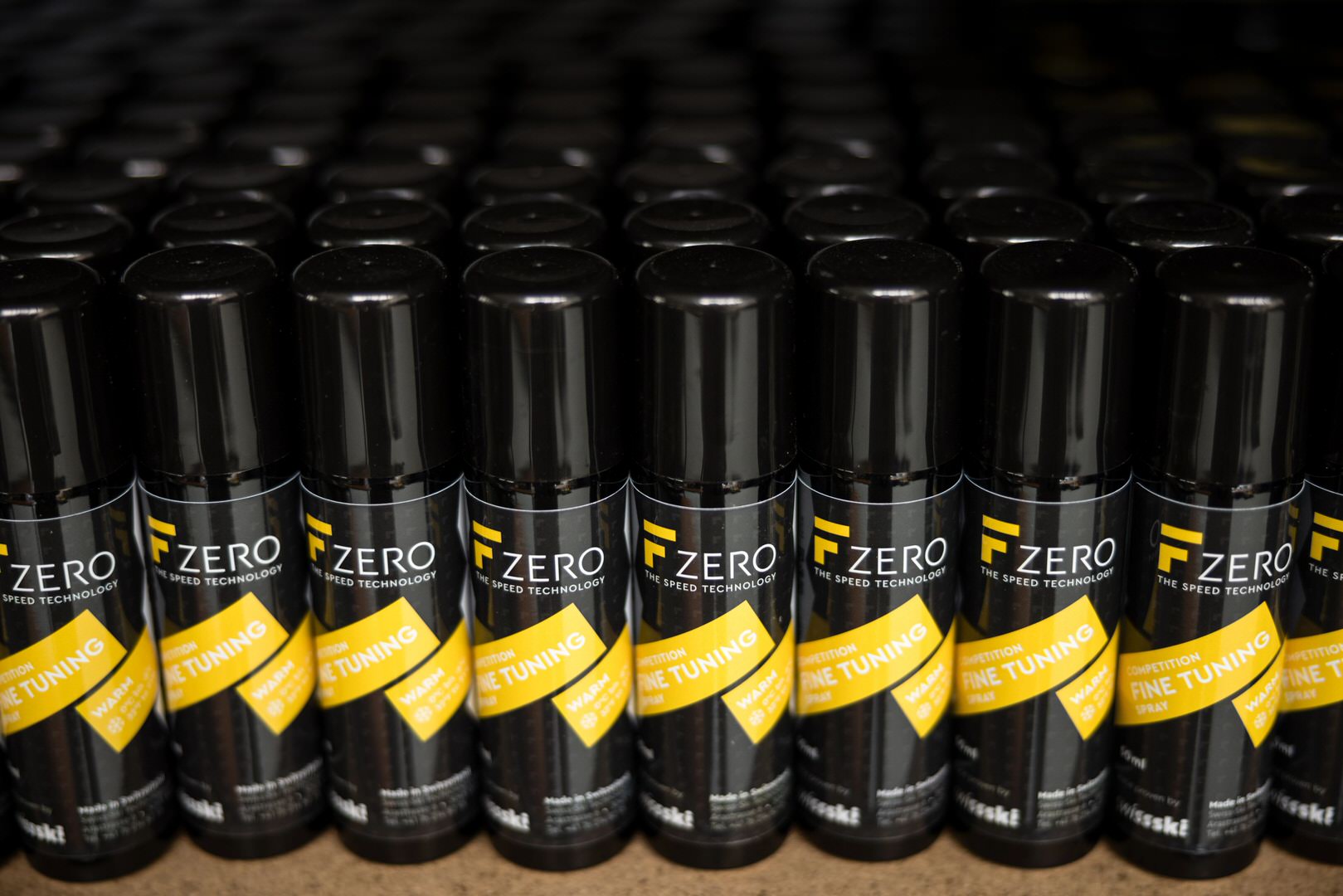 Viele schwarze FZero Spray Dosen stehen dicht an dicht in mehreren Reihen. Auf jeder Dose ist ein gelbes Etikett.