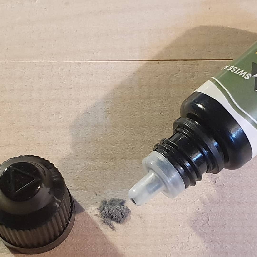 Ski Base Repair: Geöffnete Flasche mit Reparatur-Flüssigkeit und Ski Belagspulver auf hellem Untergrund.