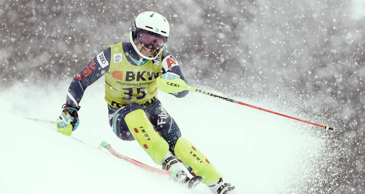 Skirennläufer in Aktion, mit Helm und Brille, Nummer 35, bei Schneefall auf der Piste.