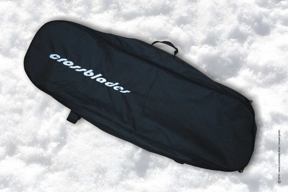 Schwarze Crossblades Tasche Schwarze Crossblades Tragetasche mit weißem Logo, liegend im Schnee.
