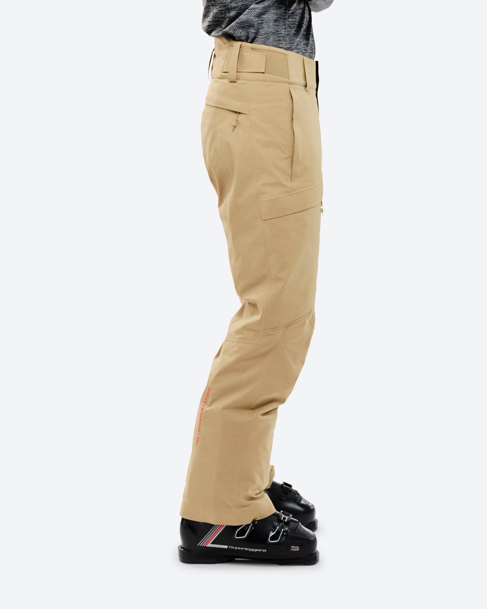 Sandfarbene GORE-TEX Skihose Sandfarbene GORE-TEX 2L Stretch Skihose am Körper mit Skischuhen, Seitenansicht.