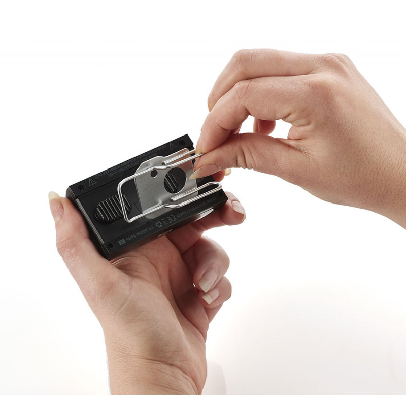 Les mains fixent un clip en fil métallique sur un C-Pack noir. Le clip est en métal et se fixe sur le côté de la batterie.