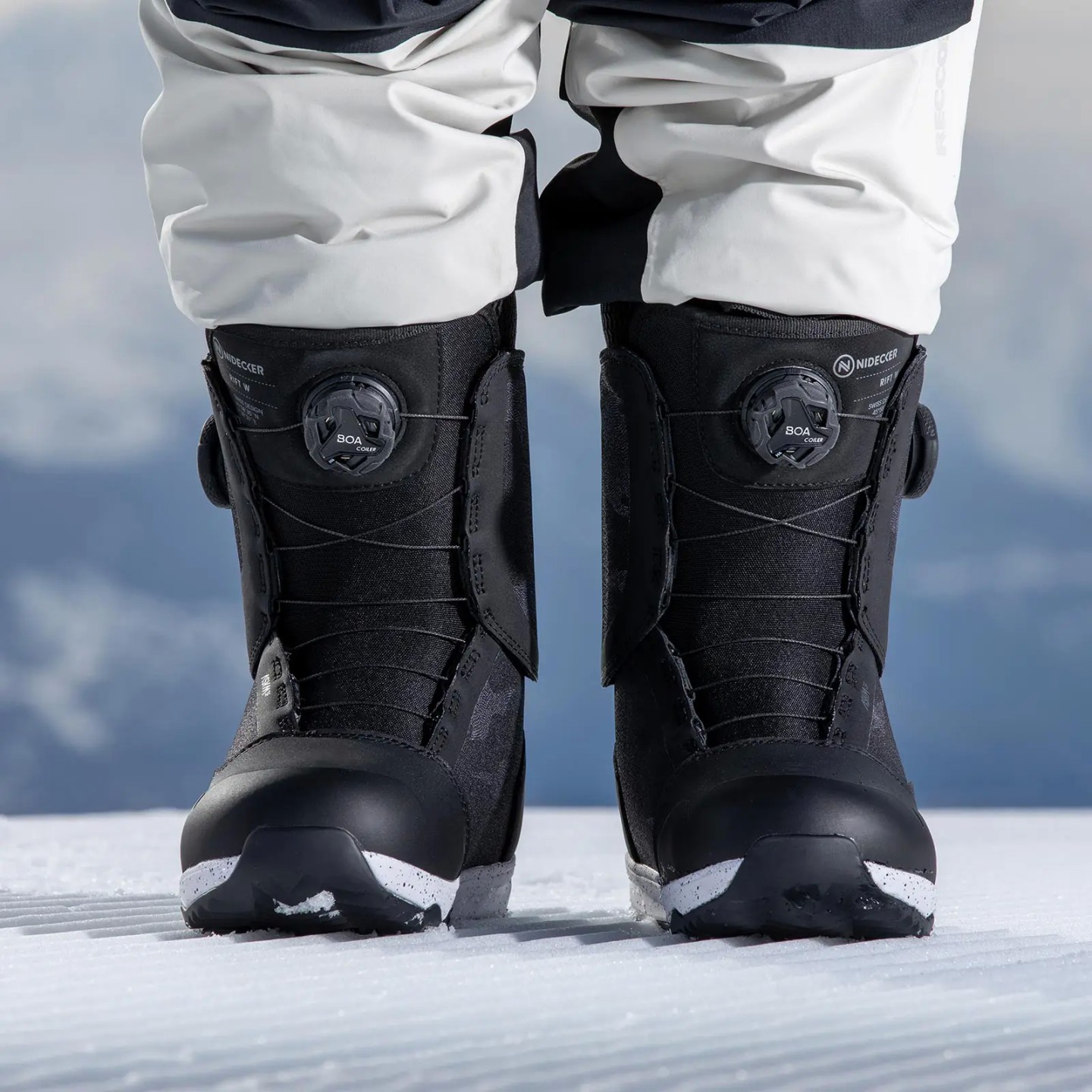 Schwarze Nidecker Rift W Snowboardschuhe mit BOA-System auf Schnee, teils von einer Person getragen.