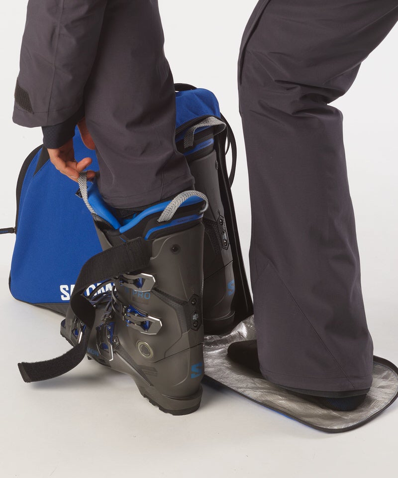 Salomon Skischuhe werden in eine blaue Original Gearbag Skischuhtasche gepackt.