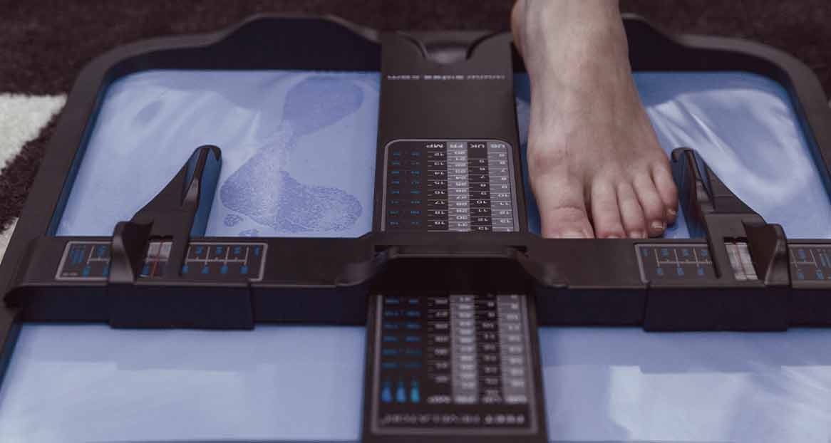 Fußmessung für Schuhe Ein Fuß wird mit einem Messgerät für die Schuhgröße vermessen; Abdrücke sind auf der Messfläche erkennbar.