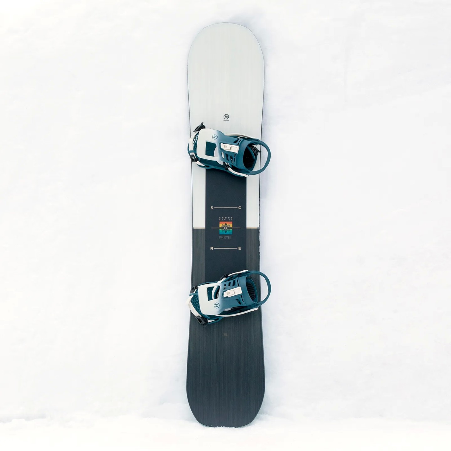 Nidecker Score Snowboard Das Nidecker Score Snowboard mit montierten Bindungen auf weißem Schnee. Das Board hat eine geteilte Farbgebung.