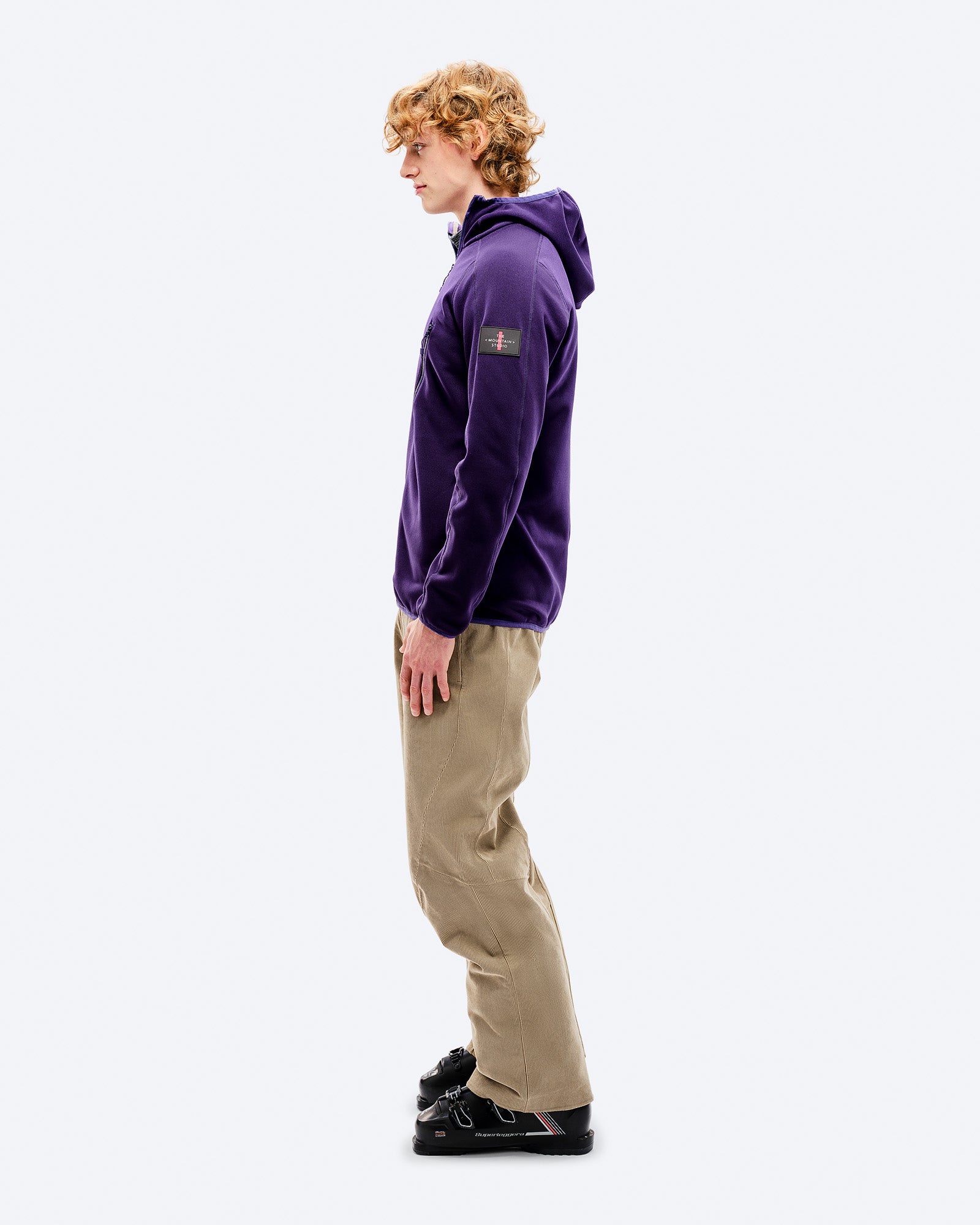 M-7 Fleece Outfit Mann trägt M-7 Tech Fleece Hood Parachute Purple, beige Hose und schwarze Schuhe im Profil.