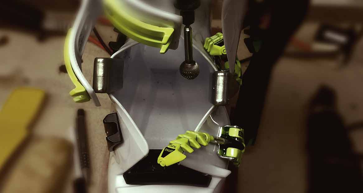 Skischuh Anpassung Ein Skischuh wird mit einem Fräser bearbeitet, um ihn an den Fuß anzupassen. Metallteile und gelbe Details sind sichtbar.