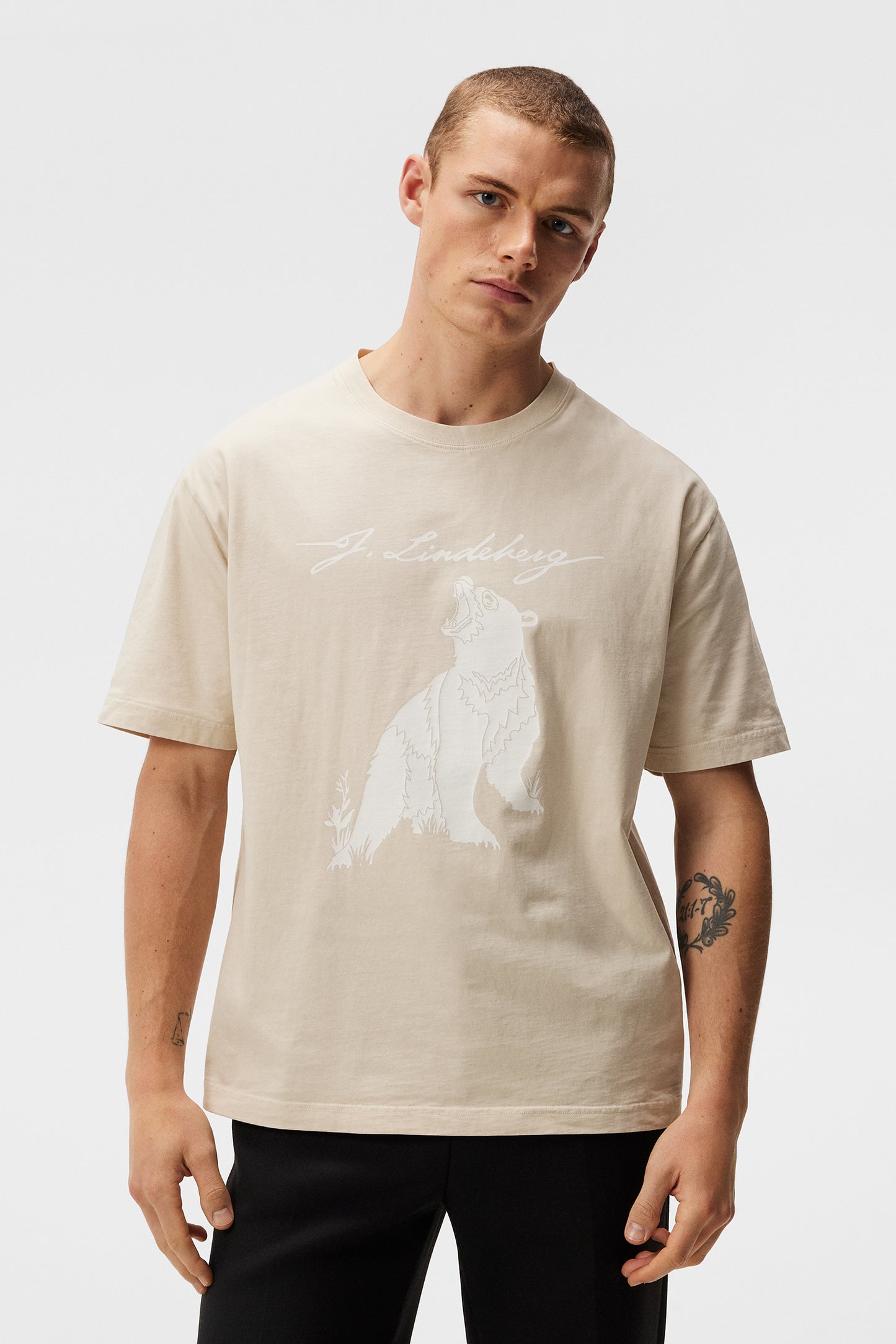 Model trägt Walsh Boxy Print Tee Oyster Gray mit Bärenmotiv und J.Lindeberg Schriftzug.