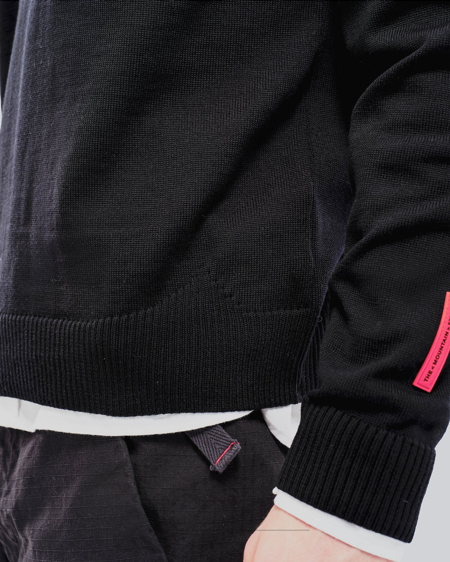 Schwarzer K-3 Ski Pullover Nahaufnahme eines schwarzen K-3 Ski Pullovers aus Merinowolle mit Rundhalsausschnitt und rotem Etikett.