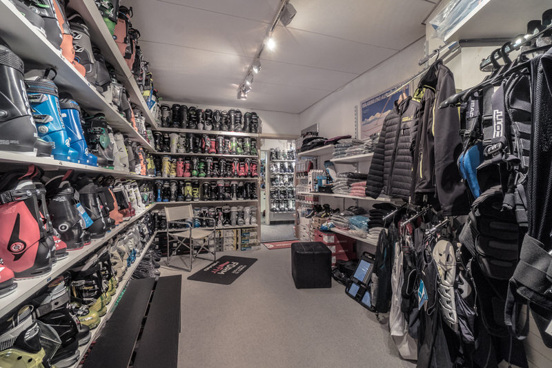 Skigeschäft Sortiment Ein Skigeschäft mit Regalen voller Skischuhe, Kleidung und Zubehör. Helle Beleuchtung und ein ordentliches Ambiente.