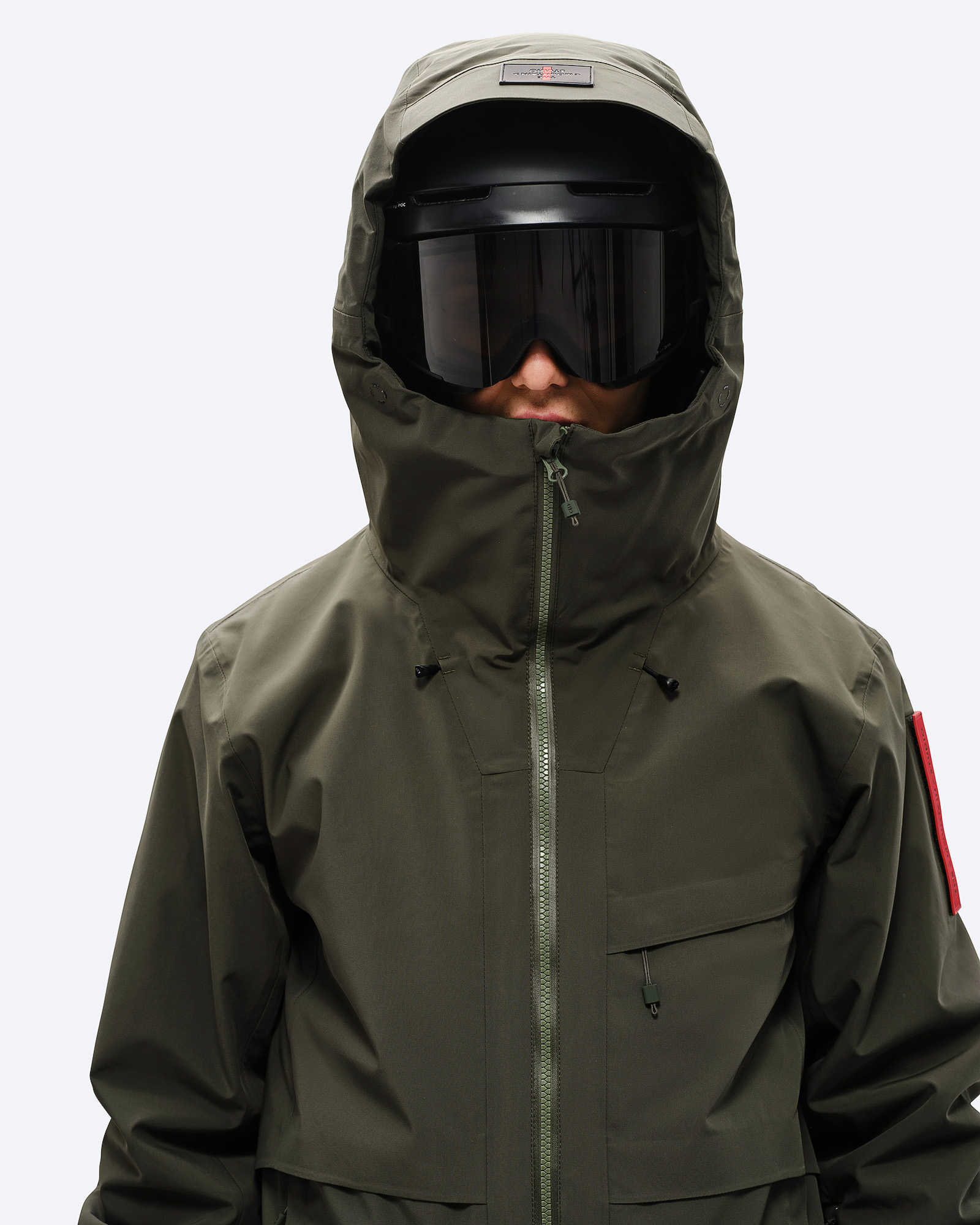 Ski-Jacke "Forest Green" Person in Ski-Jacke "Forest Green" mit Kapuze und Skibrille. Frontalansicht bis zur Hüfte.