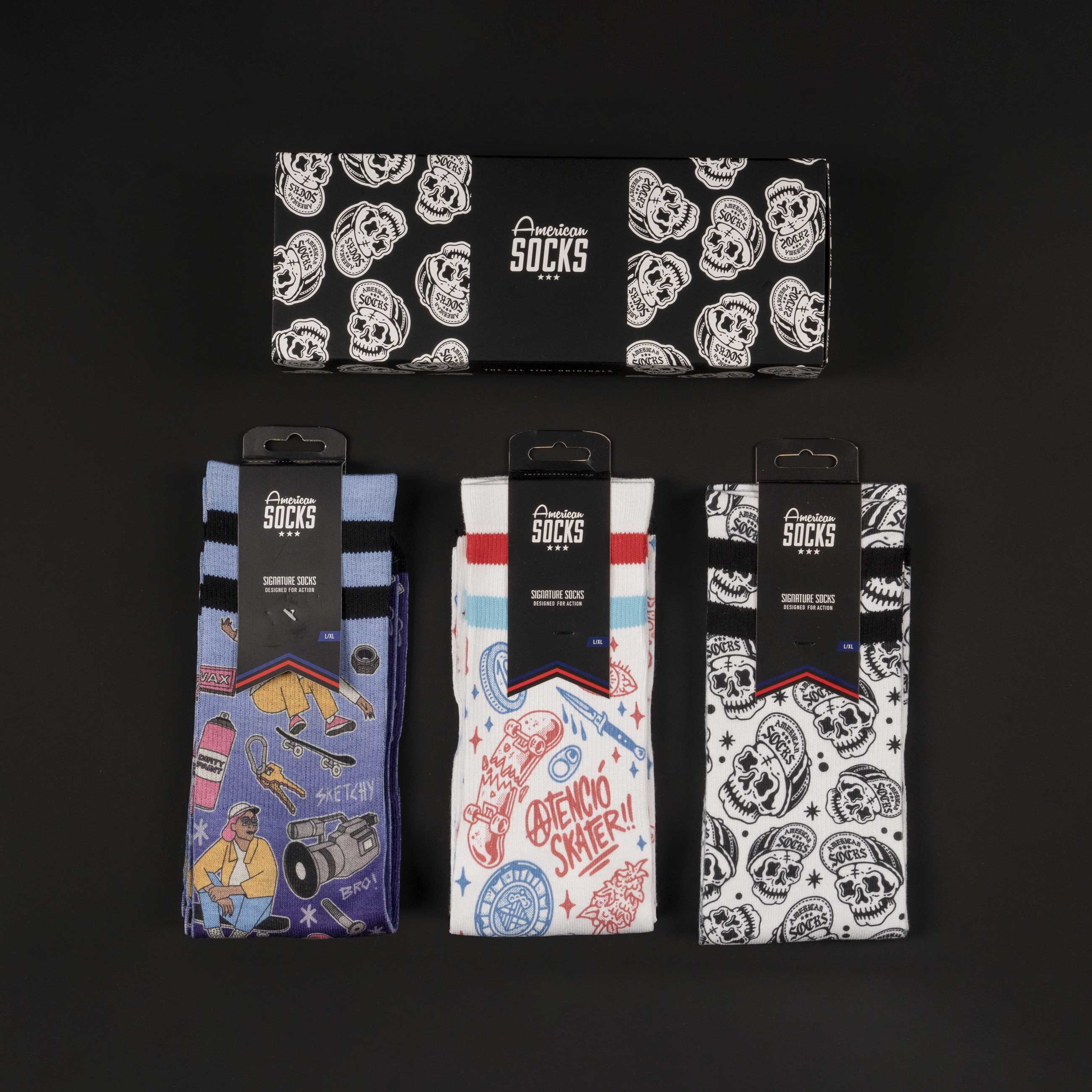 Set de chaussettes de skateur Trois paires de chaussettes American Skater avec motif, emballées dans une boîte cadeau, sur fond noir.