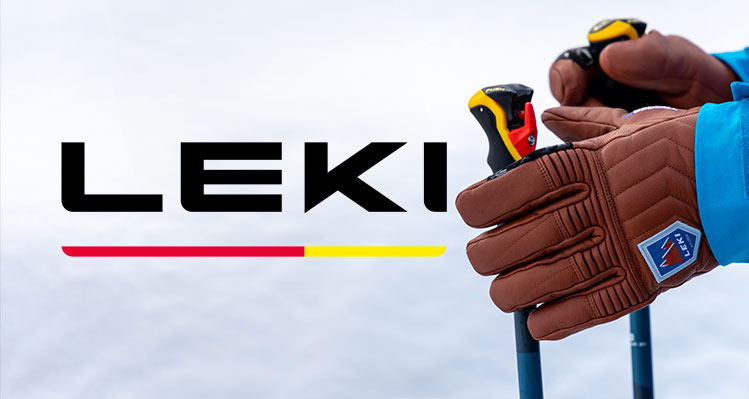 Hände in braunen Lederhandschuhen halten Skistöcke. Im Hintergrund ist das LEKI-Logo und darunter ein roter und gelber Balken.