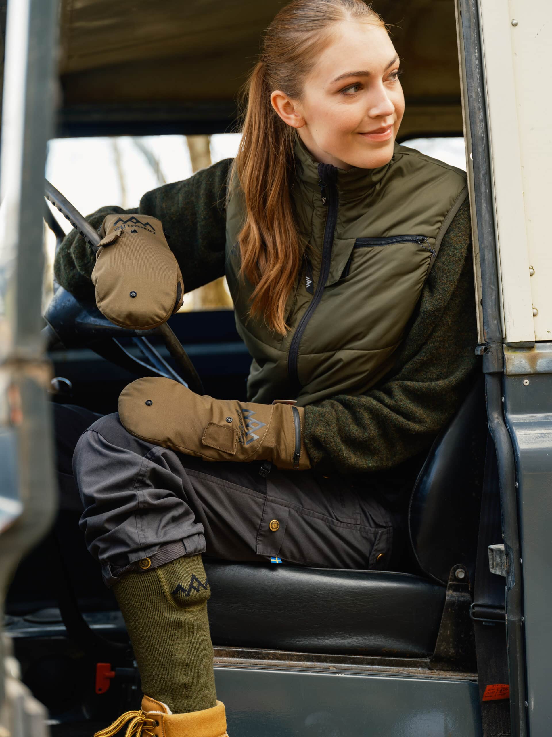 Frau im Auto mit Heizsocken Frau im Auto mit Heizsocken. Grüne Kniestrümpfe, braune Schuhe, olivgrüne Weste, beige Handschuhe.