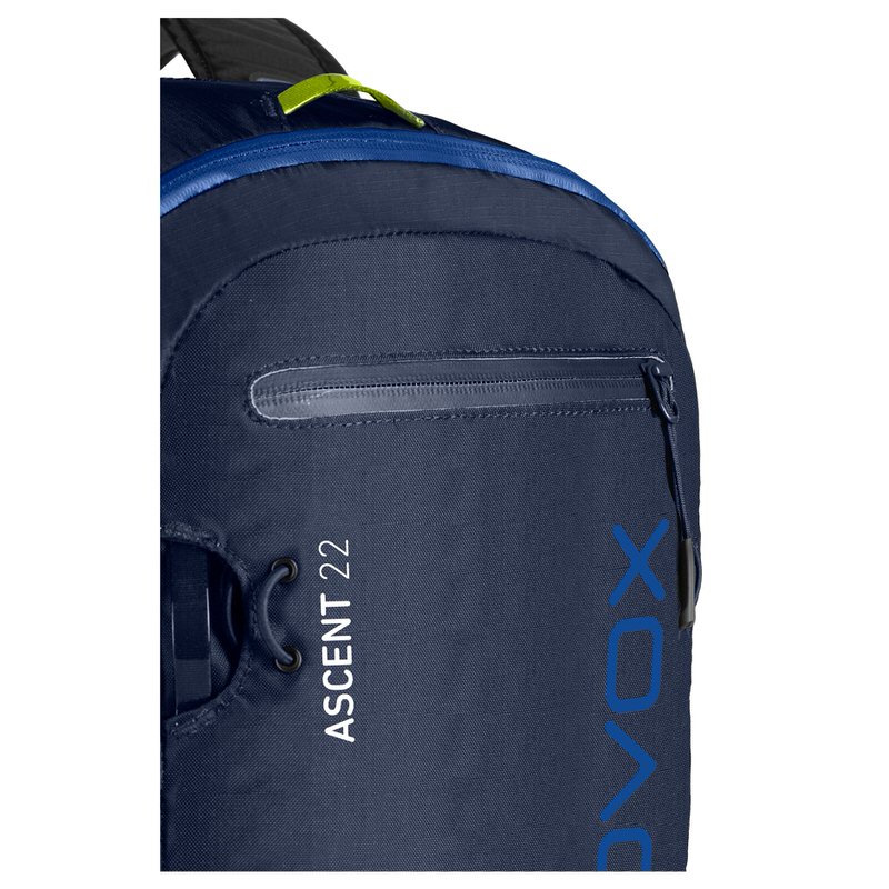 Ortovox Ascent 22 Rucksack Detailansicht: Dunkelblauer Ortovox Ascent 22 Rucksack mit Reißverschluss, Logo und seitlicher Kordelbefestigung.