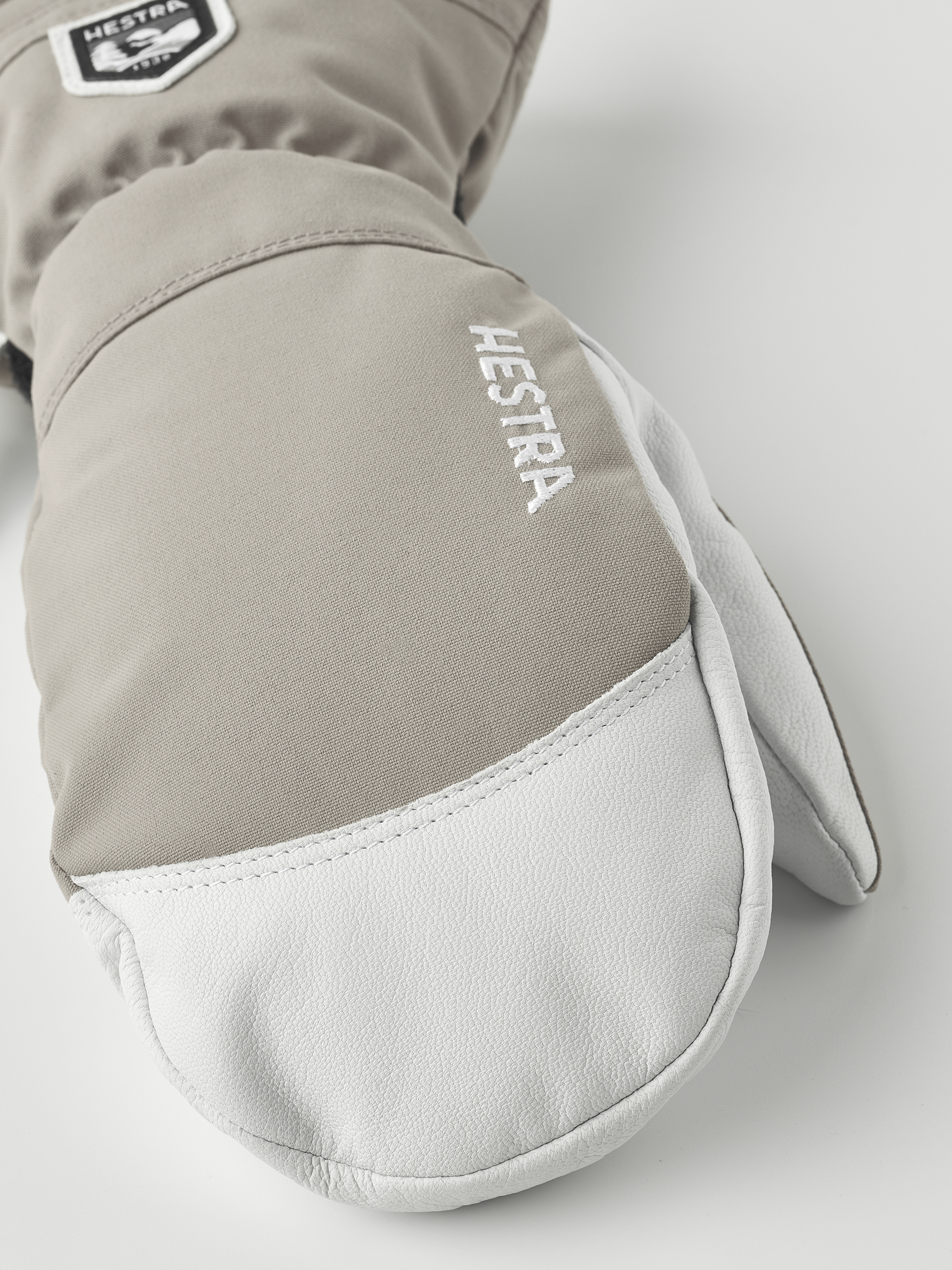 Hestra Army Leather Handschuhe Nahaufnahme eines hellbraunen Hestra Army Leather Heli Ski Mitt Fausthandschuhs mit weißem Leder an der Spitze.