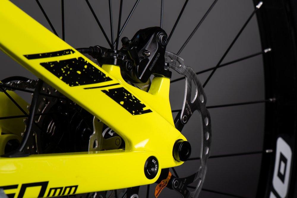 Gelbes E-Mountainbike Hinterrad Nahaufnahme des gelben Hinterbaus eines Muret 2 EP8 E-Mountainbikes mit Shimano Bremse und Bremsscheibe.