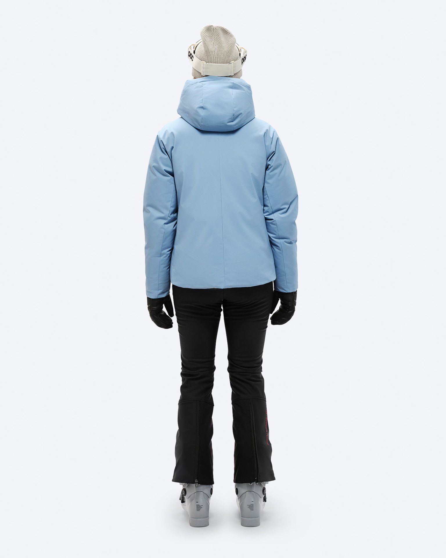 Skifahrer in blauer Daunenjacke Rückansicht einer Person in blauer Daunenjacke mit Kapuze, Skihose, Handschuhen und Skischuhen.