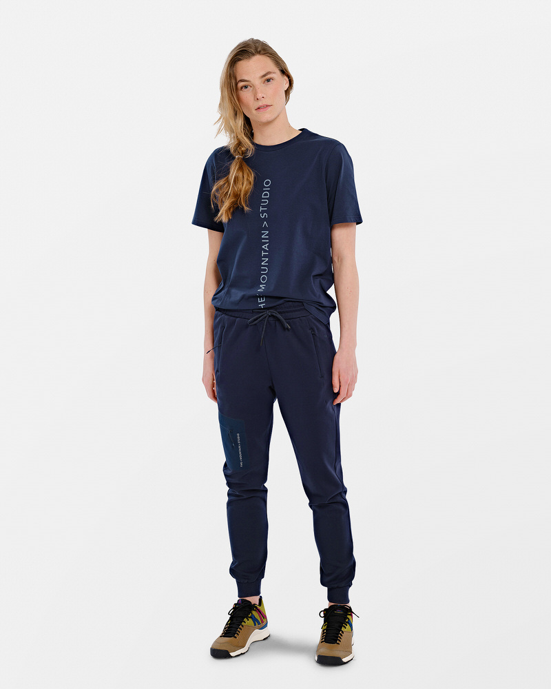 Person in marineblauem T-Shirt mit vertikalem Logo und passender Hose.