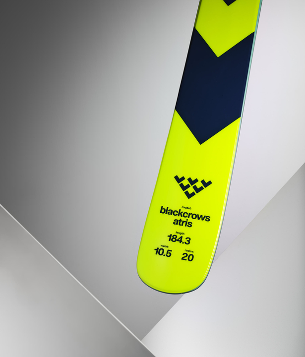 Gelber Black Crows Atris Ski Gelber Black Crows Atris Ski mit technischen Details auf grauem Hintergrund.